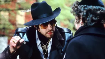 Adam Sandler en PIMP juif, avec grandes lunettes de soleil et chapeau, menace avec son poing un homme que l'on voit de dos, en amorce, dans le film The Hebrew Hammer.