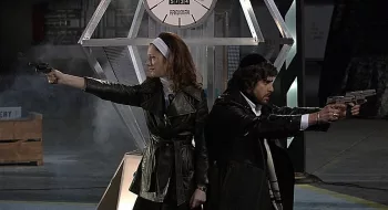 Un rabbin, avec kippa, et une femme vêtue d'un manteau en cuir, dégainent leur pistolet dos à dos dans The Hebrew Hammer.