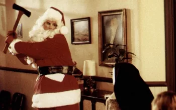 Un Père Noël dans le salon d'une maison vieillotte s'apprête à donner un coup de hache à une victime sur le canapé dans le film Douce nuit, sanglante nuit.
