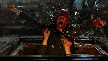 Vu du dessus un homme en sang est expulsé d'une fenêtre qui vole en éclats, dans le film Le jour de la bête.