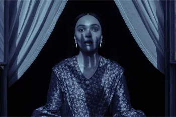 Lilly Rose Depp au bord d'une fenêtre, angoissée, de nuit ; l'ombre de main de Nosferatu plane sur son visage.