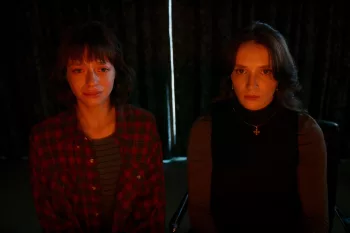 Les deux héroïnes du film Les chambres rouges sont assises côte à côté, rideau tirée derrière elles et observent devant elles une lumière jaune qui éclaire leurs visages ; l'une d'entre elles pleure.