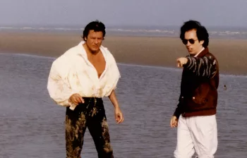 René Manzor dirige Alain Delon sur une plage, au bord de l'océan.