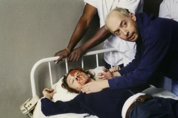 René Manzor sur le tournage de Dédales, donnant des indications au dessus de Sylvie Testud ensanglantée, dans un lit d’hôpital blanc.