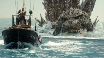 Une frégate sur la mer est poursuivie par Godzilla qui fonce vers elle au bord de l'eau ; scène du film Godzilla Minus One.