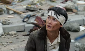 Koicihi, un bandeau sur le crâne, observe le ciel au milieu des ruines occasionnées par le lézard géant, dans le film Godzilla Minus One.