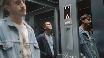 Paul Mescal et Andrew Scott dans un ascenseur, Mescal à gauche, Scott au centre de l'image dont nous ne voyons que le reflet dans la vitre ; le reflet de Mescal, lui, sur la vitre de droite n'a étrangement pas la même attitude que le "vrai" ; plan issu du film Sans jamais nous connaître.