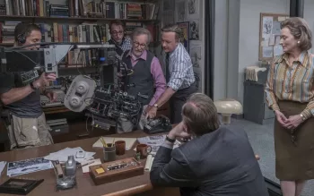 Steven Spielberg donne ses indications au cadreur, portant une grosse caméra, sur le tournage d'une scène de Pentagon Papers, dans un salon avec une large bibliothèque ; Meryl Streep attend patiemment debout, les mains jointes.