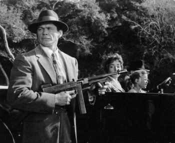 Charles Bronson surveillle une femme et une jeune fille dans une décapotable, habillé en gangster des années 20, portant une vielle mitraillette dans le film Mitraillette Kelly projeté à l’Extrême cinéma de Toulouse.