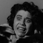 Gros plan, en noir et blanc sur une femme apeurée, des mains, en ombre, tentent de l'étrangler ; issu du film Dementia projeté au festival Extrême CInéma 2024.