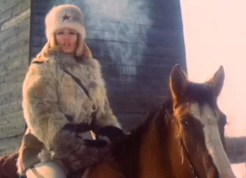 Ilsa, gardienne du goulag, est sur son cheval, en tenue d'hiver, de la vapeur s'échappe de sa bouche.