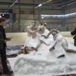 Deux policiers font le tour de cadavres pris dans un gros blocs de glace, au beau milieu d'une patinoire pour hochey sur glace ; scène de True Dtective : Night Country.