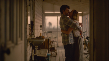 Un jeune couple s'embrasse sur la terrasse-veranda de leur pavillon dans le film Foe.