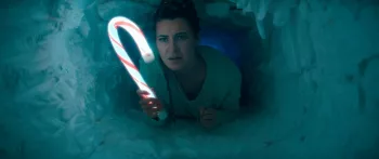 Une femme rampe dans un tunnel de glace, s'éclairant avec une lampe en forme de sucre d'ogre dans le film A Creature Was Stirring.
