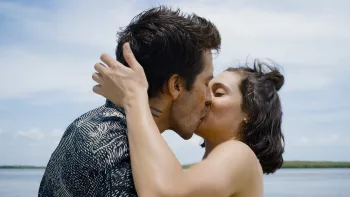 Un baiser fougueux sur une plage, entre un homme et une femme, cheveux aux vents, dans le film Road House.