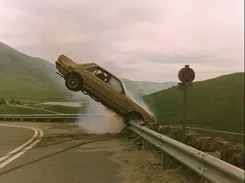 Une voiture en train de s'encastrer, comme tombant du ciel, dans la rembarde qui borde une route de montagnes vertes dans le film The appointment diffusé au festival Extreme Cinéma.