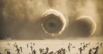 Un immense vers de sable apprête à dévorer de nombreux habitants du désert qui fuient ; scène de Dune : deuxième partie.