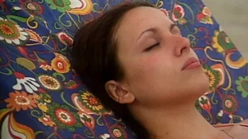 La jeune Ana Belén sur une chaise de plage aux motifs floraux, les yeux fermés, dans le film La créature.