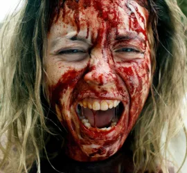 Gros plan sur une le visage d'une jeune femme hurlant, couverte de sang dans le film Immaculée.
