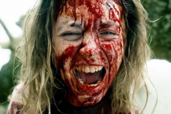 Gros plan sur une le visage d'une jeune femme hurlant, couverte de sang dans le film Immaculée.