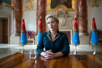 Kate Winslet en présidente, assise dans une salle luxueuse, les mains jointes, attentive ; derrière elle, cinq drapeaux du pays fictif de la série The Regime.