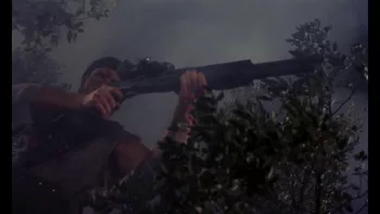 Surgissant d'un bosquet, plongé dans une brume épaisse, un soldat vise avec un énorme fusil à pompe dans le film Blastfighter.