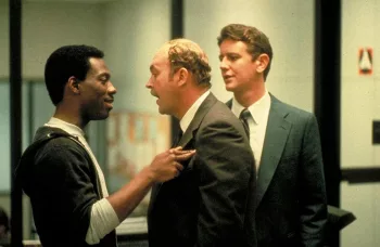Eddie Murphy se fait sermonner par son responsable hiérarchique dans le film Le flic de Beverly Hills ; goguenard, Murphy repousse avec un sourire et du bout du doigt son supérieur, dans les locaux de la police.