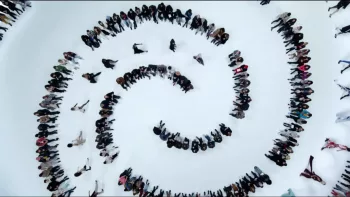 Plan en contre-plongée, réalisé par Xavier Legrand, sur une foule sur le neige qui se place de sorte à dessiner une spirale.