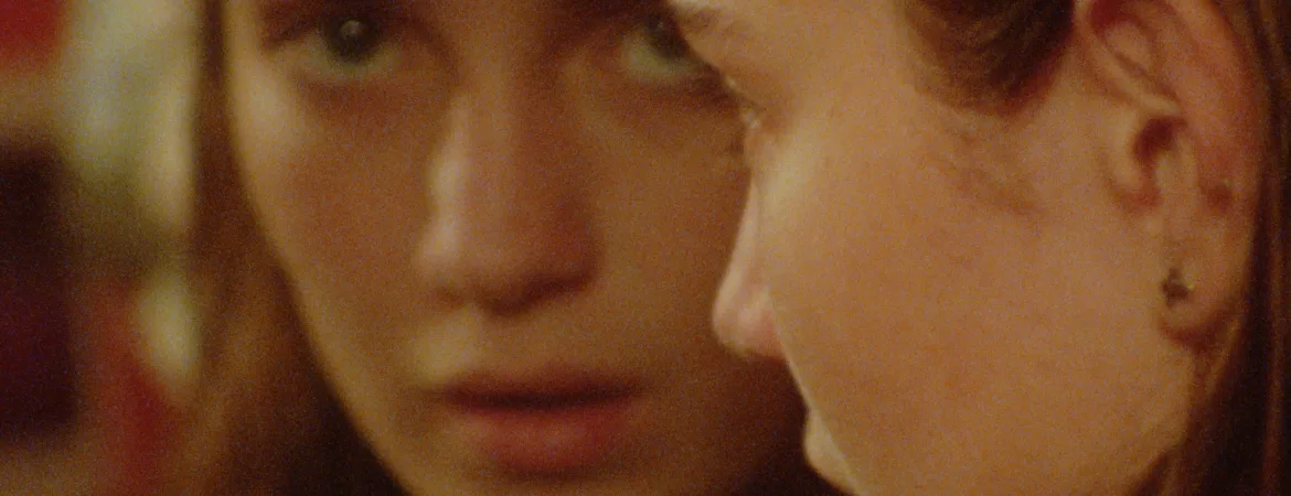 Gros plan sur le visage de Taila Ryder qui se regarde dans le miroir, avec un air méfiant, dans le film Sweet East.