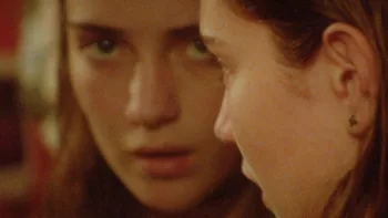 Gros plan sur le visage de Taila Ryder qui se regarde dans le miroir, avec un air méfiant, dans le film Sweet East.