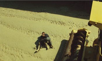 Deux hommes se bagarrent, au sol, près d'une moissonneuse dans le film Peaux de vaches.