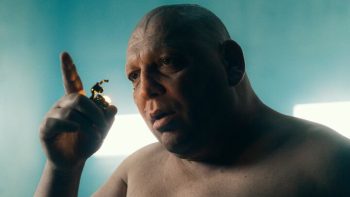 Un homme hagard, chauve et torse nu, observe la flamme du briquet qu'il tient dans sa main, dans La plateforme 2.