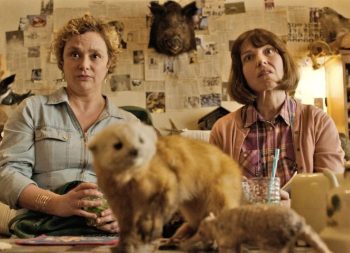 Deux femmes, l'air interrogateur et perplexe, sont assises sur le canapé d'un salon entièrement consacré à la taxidermie, avec une tête de sanglier au mur, un furet empaillé sur la table basse, et des murs tapissés de coupures de journaux ; scène du long-métrage Les pistolets en plastique.