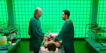 Dans une salle toute éclairée en vert fluo, deux médecins légistes, se font face et semblent discuter tranquillement tout en ayant les mains dans un corps d'homme ouvert ; scène du film Les pistolets en plastique.