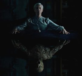 Visuel promotionnel d'Oddity où l'on voit comme un miroir vertical, Carolyn Bracken assise, dans la pénombre, et sous elle un reflet dans la même position montrant un monstre.