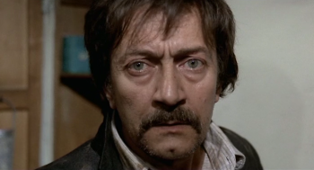 Plan rapproché-épaule, de face, sur l'acteur Gualtiero Rispolis, la mine creusée, le regard inquiet ; issu du film Chassés-croisés sur une lame de rasoir.