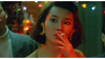 Plan rapproché-épaule sur Maggie Cheung, dans un bar, une cigarette à la bouche dans le film Les guerriers du temps.