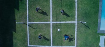 Plongée zénithale sur quatre silhouettes, sur une pelouse, dans quatre carrés tracés à la craie blanche sur le sol ; issu du film Cuadrilatero projeté au FIFIGROT 2025.