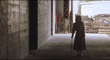 Une femme avec une canne marche dans un hangar dessafecté dans Serpent's Path de Kiyoshi Kurosawa