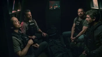 Quatre policiers en tenue d'intervention avec gilets pare-balles, discutent à l'arrière d'un camion de police blindé dans le film The rip.