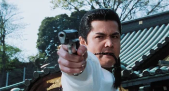 Riki Takeuchi dégaine son revolver devant un temple, en plein jour, dans le film Graine de yakuza.