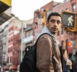 Riz Ahmed méfiant dans une rue bondée, regarde par dessus son épaule ; scène du film L'intermédiaire.