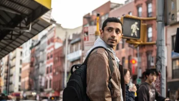 Riz Ahmed méfiant dans une rue bondée, regarde par dessus son épaule ; scène du film L'intermédiaire.