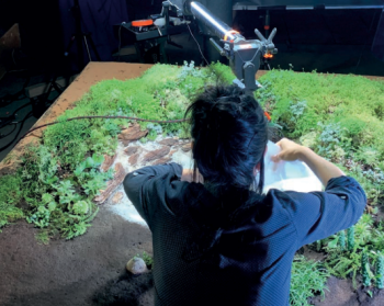 Momoko Seto sur le tournage de Planètes, au-dessus d'une maquette représentant de l'herbe et des végétaux. 