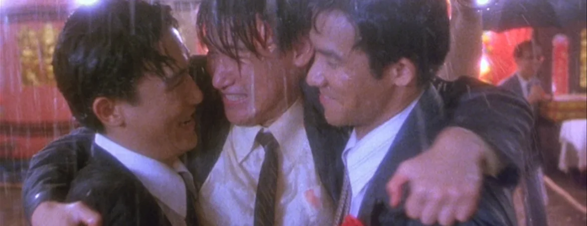 Les trois amis d'Une balle dans la tête, en tenue de mariage, bras dessus bras dessous sous la pluie.