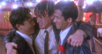 Les trois amis d'Une balle dans la tête, en tenue de mariage, bras dessus bras dessous sous la pluie.