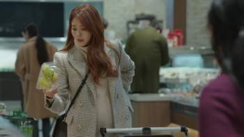 Han So-Hee dans une scène de World of the Married où elle observe en boutique un verre.