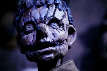 On aperçoit en gros plan le visage d'un pantin en bois ; l'image est dans des tons bleus ; le pantin a les yeux grand ouverts ; il a des cheveux de bois bleus ; plan du film PINOCCHIO UNSTRUNG, projeté au BIFFF 2026.