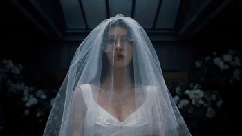 Une mariée apparaît en plan rapproché ; elle porte une robe blanche et un voile blanc translucide est rabattu sur son visage ; la pièce est sombre autour d'elle et l'on peine à reconnaître l'environnement ; plan de la Saison 1 de UN TRES MAUVAIS PRESSENTIMENT, série Netflix.