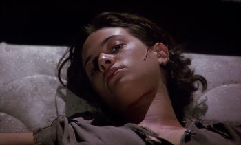 Une jeune femme (Asia Argento) semble couchée ; on ne voit que son visage et le haut de son buste ; sa joue gauche est marquée d'une entaille ensanglantée ; elle porte des cheveux noirs et regarde vaguement vers la caméra ; plan du film LE SYNDROME DE STENDHAL de Dario Argento.